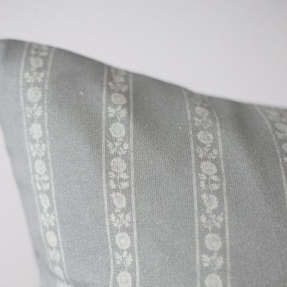 Gray pillow with white floral stripe pattern running vertically down the center.