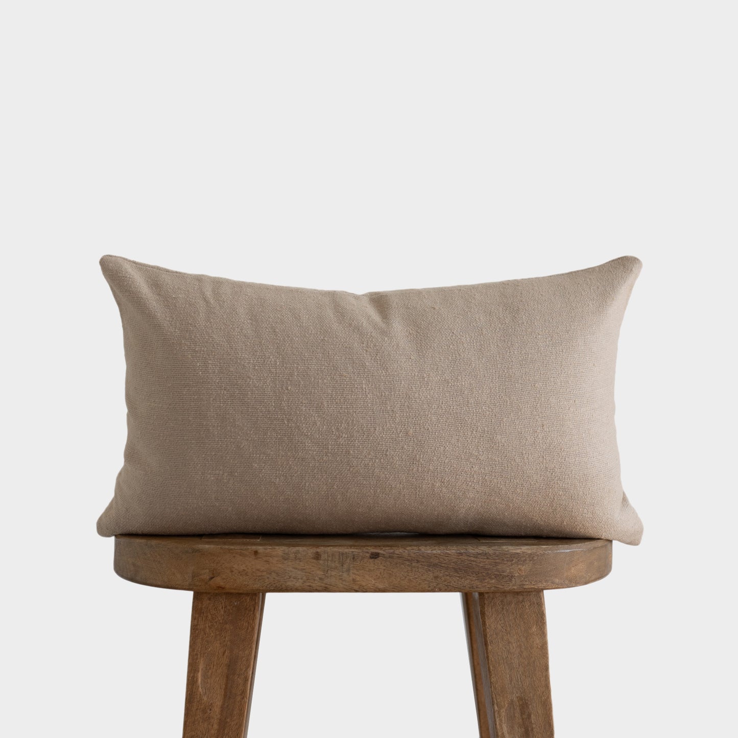 Beige boucle rectangular pillow with textured weave displayed on wooden chair.