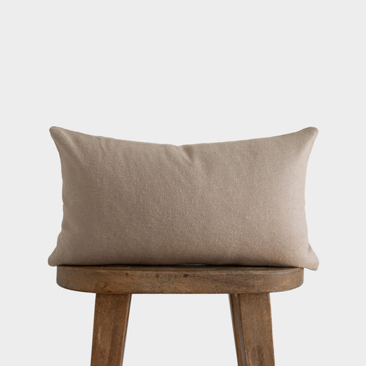 Beige boucle rectangular pillow with textured weave displayed on wooden chair.