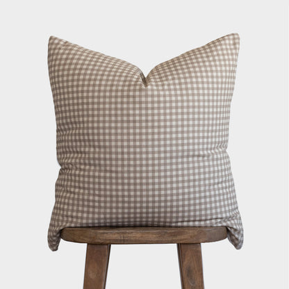 Tan and white gingham patterned pillow cover displayed on wooden stool.