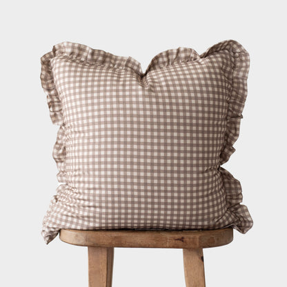Tan and white gingham pillow with ruffled edges on all sides, displayed on a wooden stool.