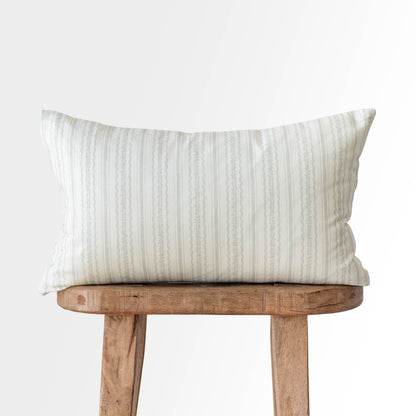 Cream and gray striped rectangular pillow with textured weave sitting on wooden stool.