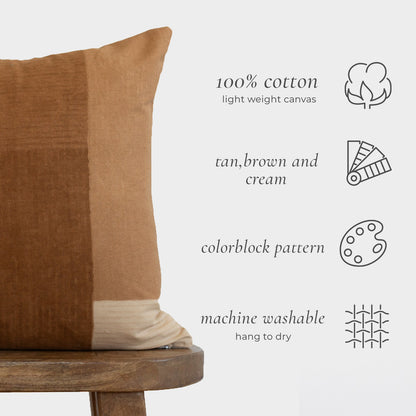 Tan, brown, and cream colorblock cotton canvas pillow with vertical stripe pattern on wooden stool.