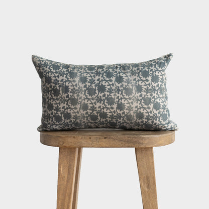 Gray and cream patterned rectangular pillow with damask design resting on wooden stool.
