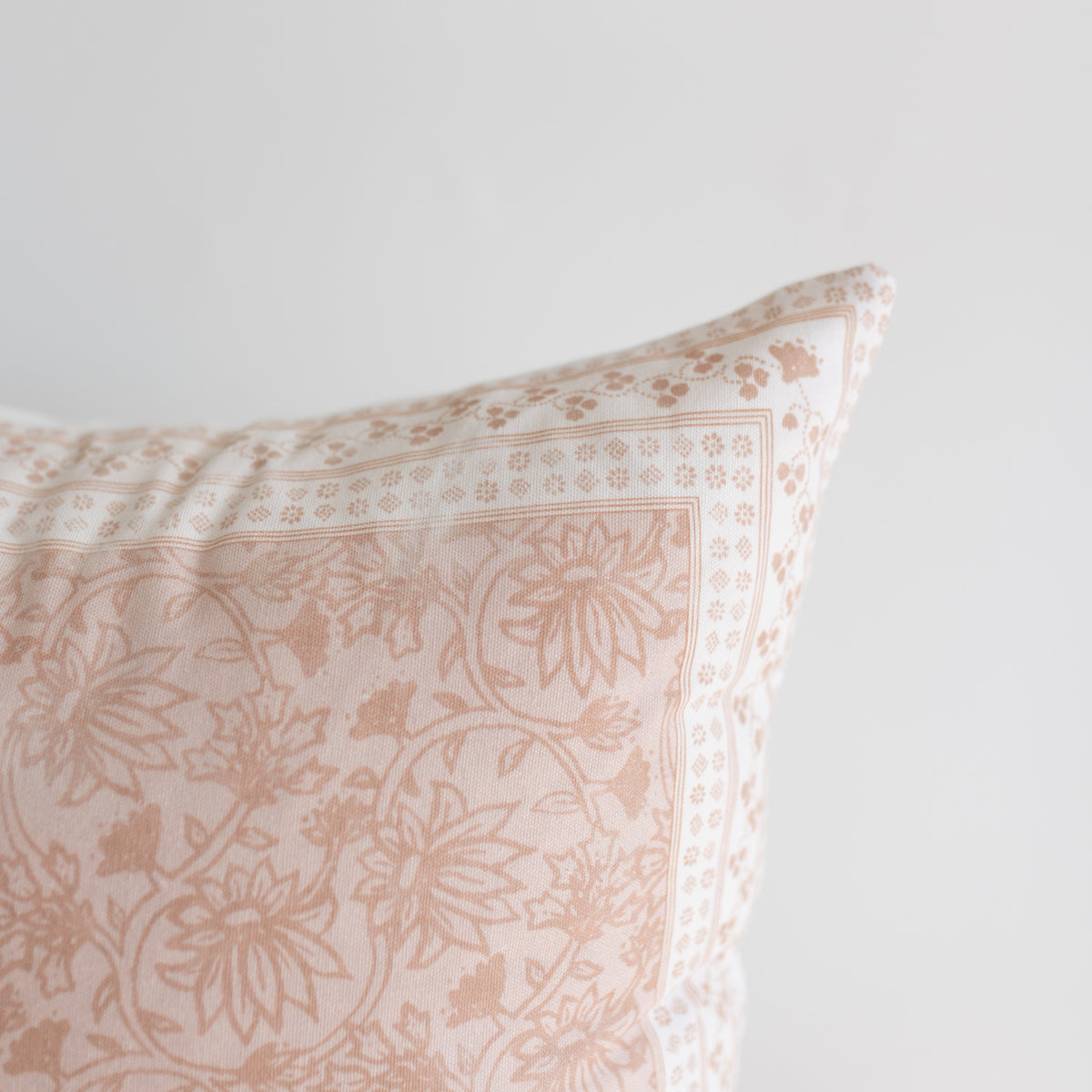Beige and cream pillow with floral and geometric patterned fabric in contrasting tones.