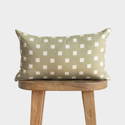Olive-green rectangular pillow with white spaced check pattern, displayed on wooden stool.