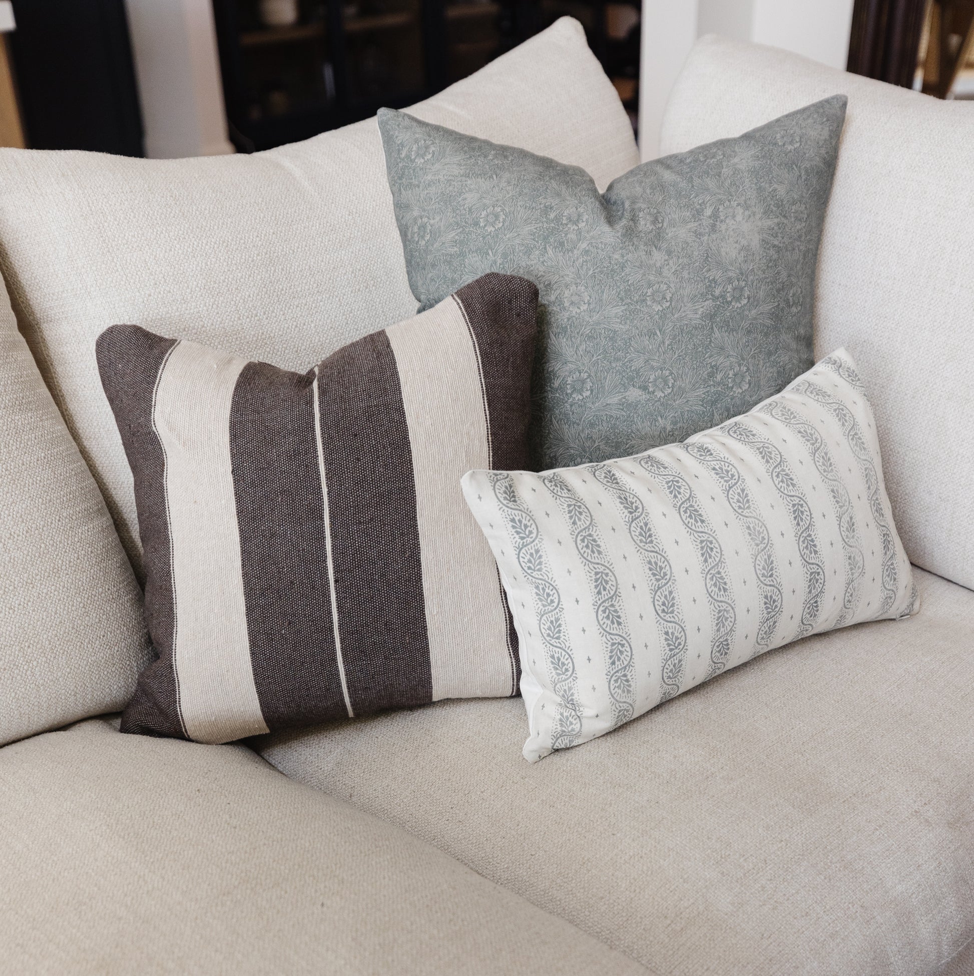 Ira lumbar pillow with vertical brown and cream stripes and piping detail on neutral sofa.