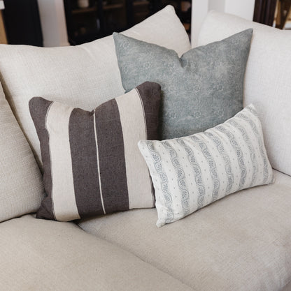 Ira lumbar pillow with vertical brown and cream stripes and piping detail on neutral sofa.