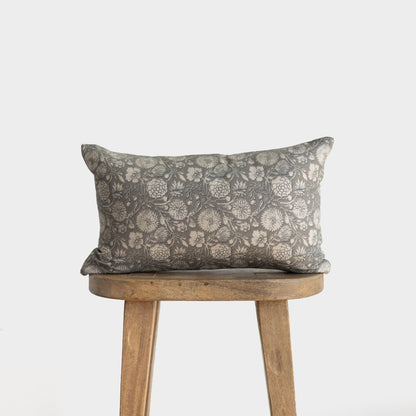 Gray floral patterned rectangular pillow with botanical print displayed on wooden stool.