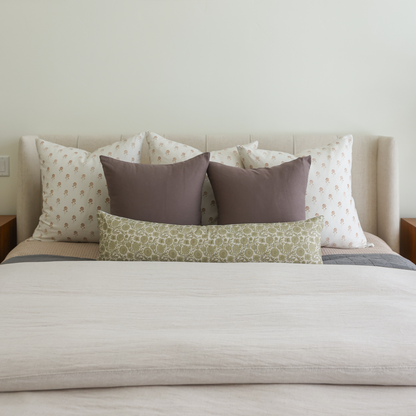 Green patterned lumbar pillow displayed on a bed with coordinating throw pillows and neutral bedding.