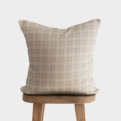 Taupe linen pillow with subtle grid pattern displayed on wooden chair.