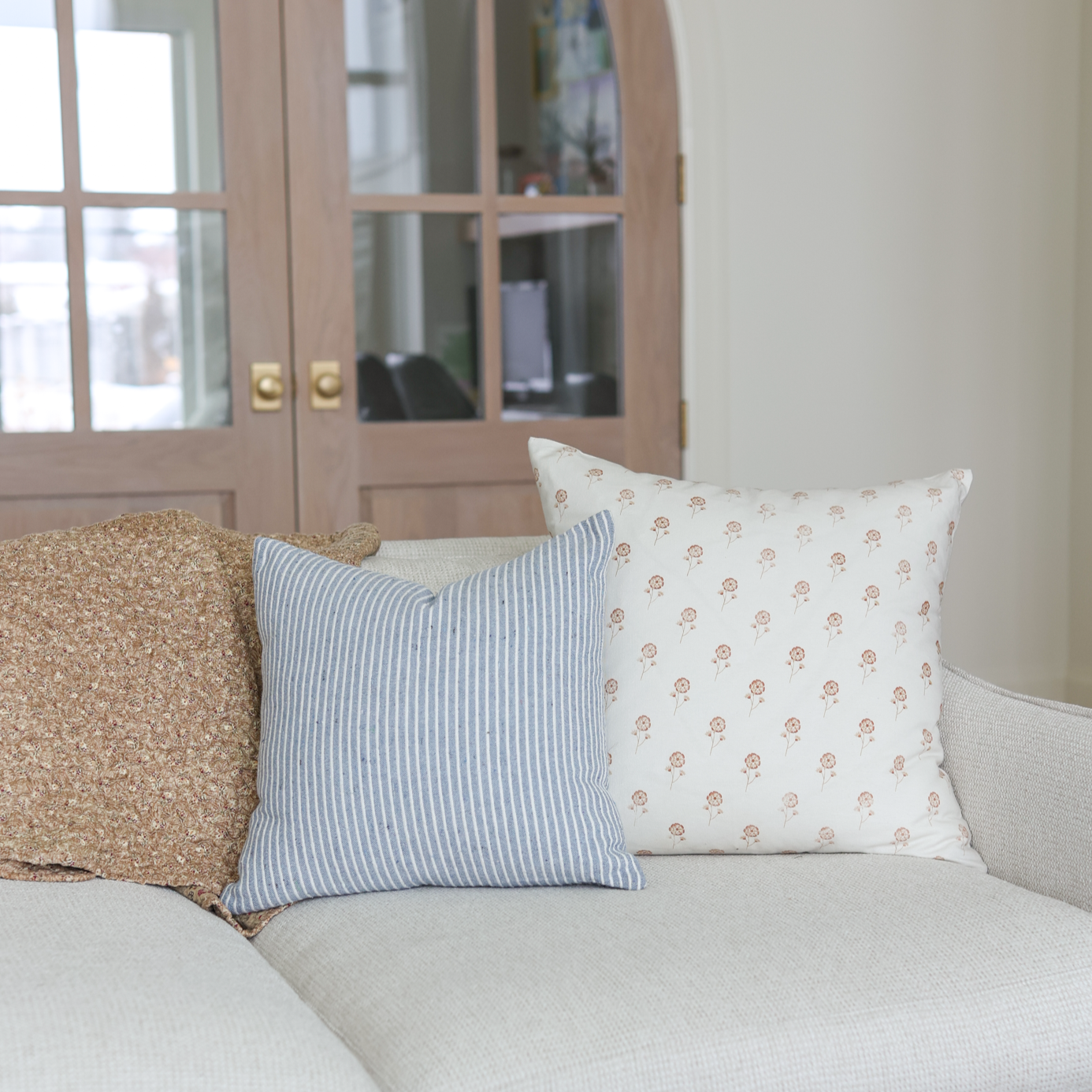 Blue and white striped decorative pillow displayed on a light gray sofa.