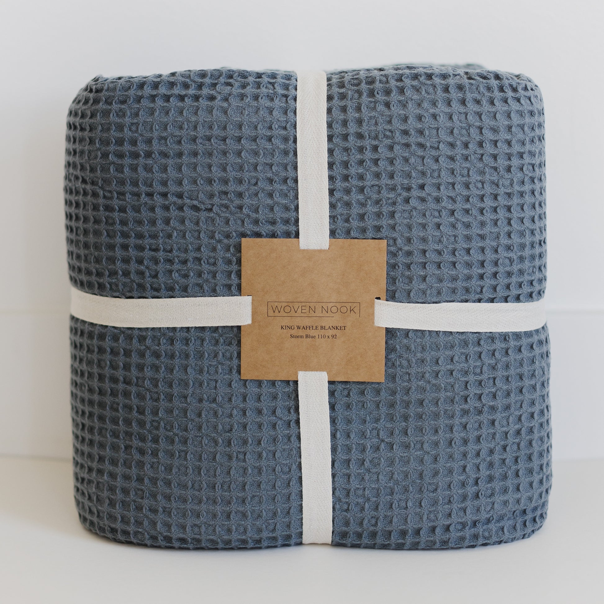 Storm blue waffle blanket rolled and wrapped with white bands and kraft paper label.