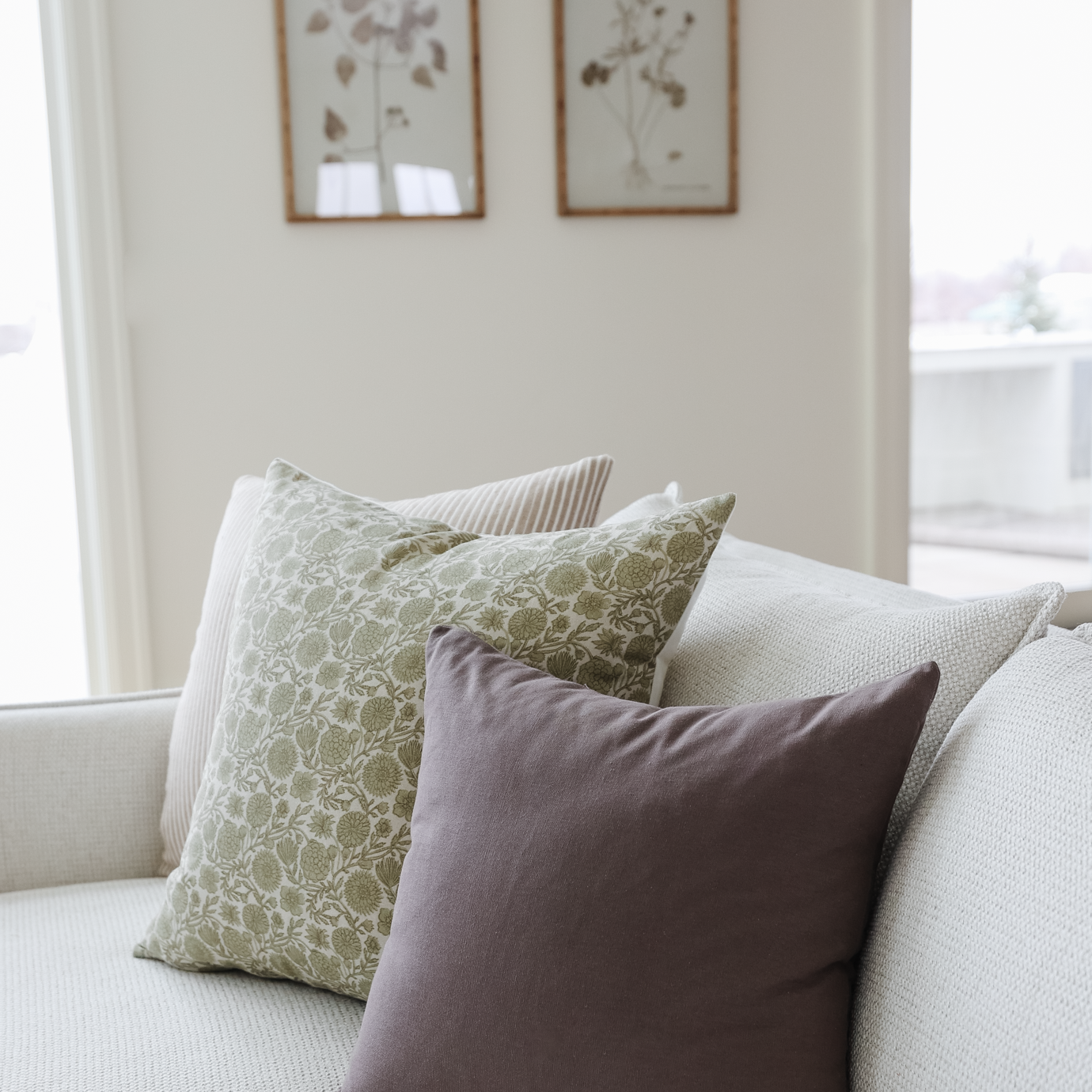 Green and white damask patterned pillow displayed on a light gray sofa with coordinating pillows.