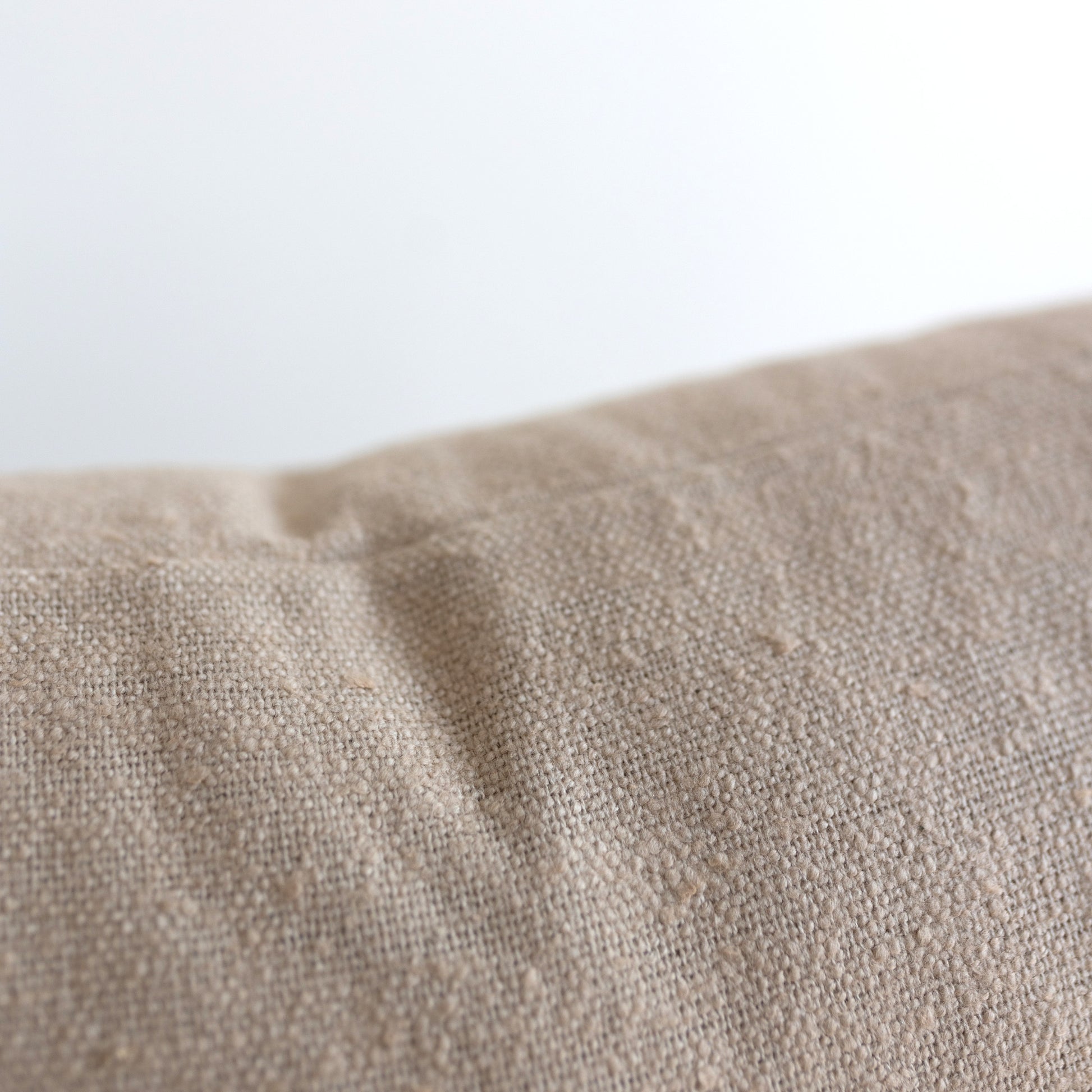 Beige boucle fabric with textured looped surface and visible weave pattern.