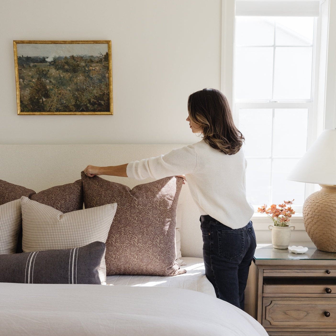 Brown damask patterned pillow displayed on a bed with neutral bedding and decorative pillows.