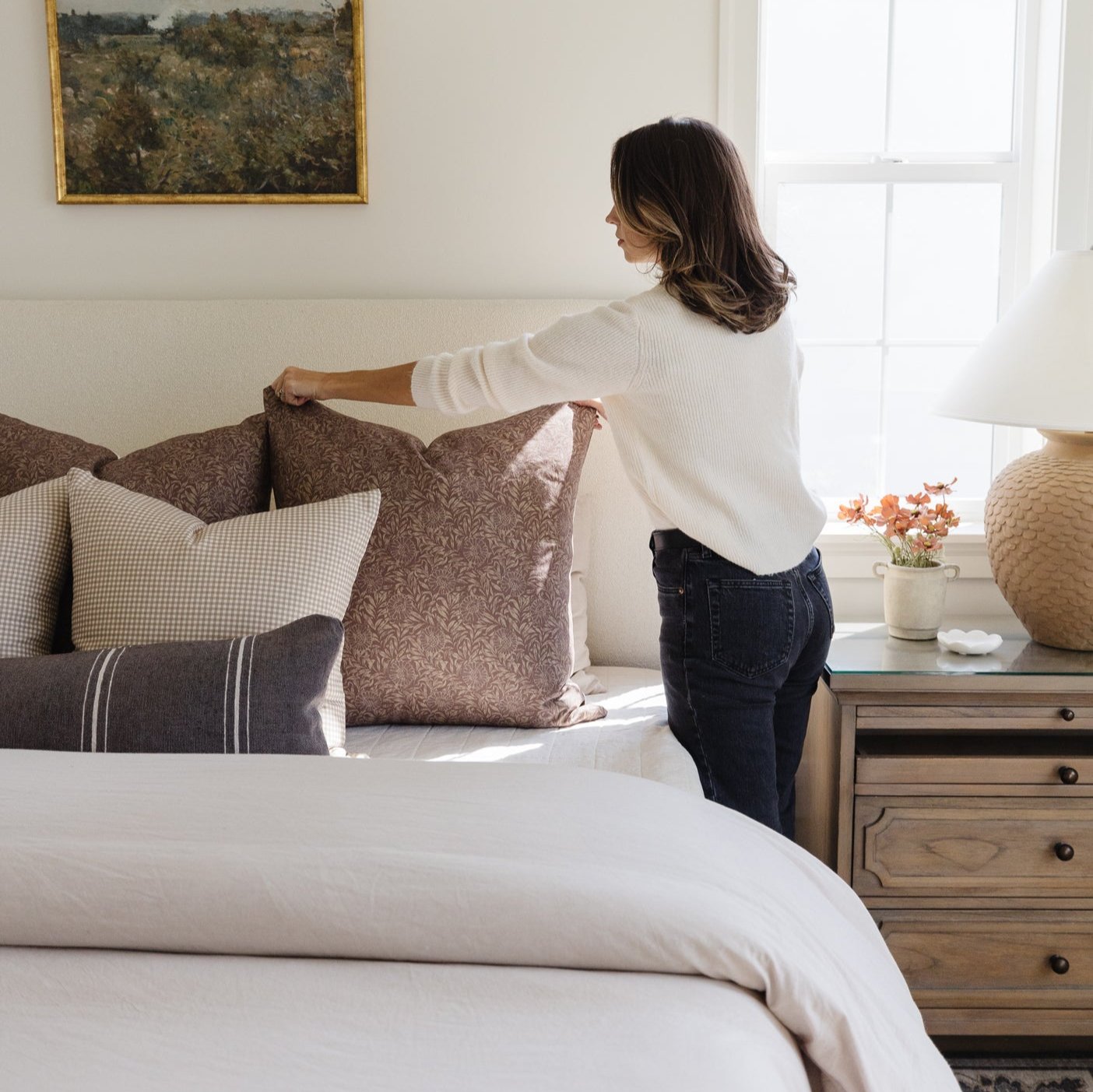 Warm charcoal lumbar pillow with subtle texture displayed on a bed with coordinating pillows in a bedroom setting.