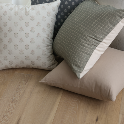 Four tan and neutral decorative pillows in varying patterns displayed on wood flooring.