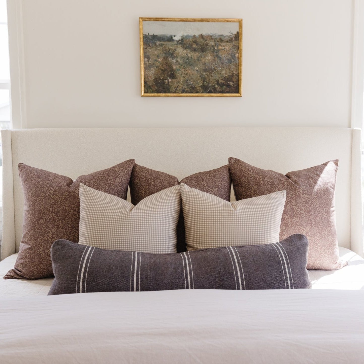 Charcoal lumbar pillow with vertical striped pattern displayed on bed with coordinating decorative pillows.