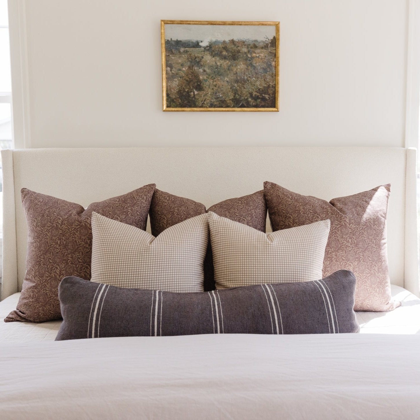 Charcoal lumbar pillow with vertical striped pattern displayed on bed with coordinating decorative pillows.