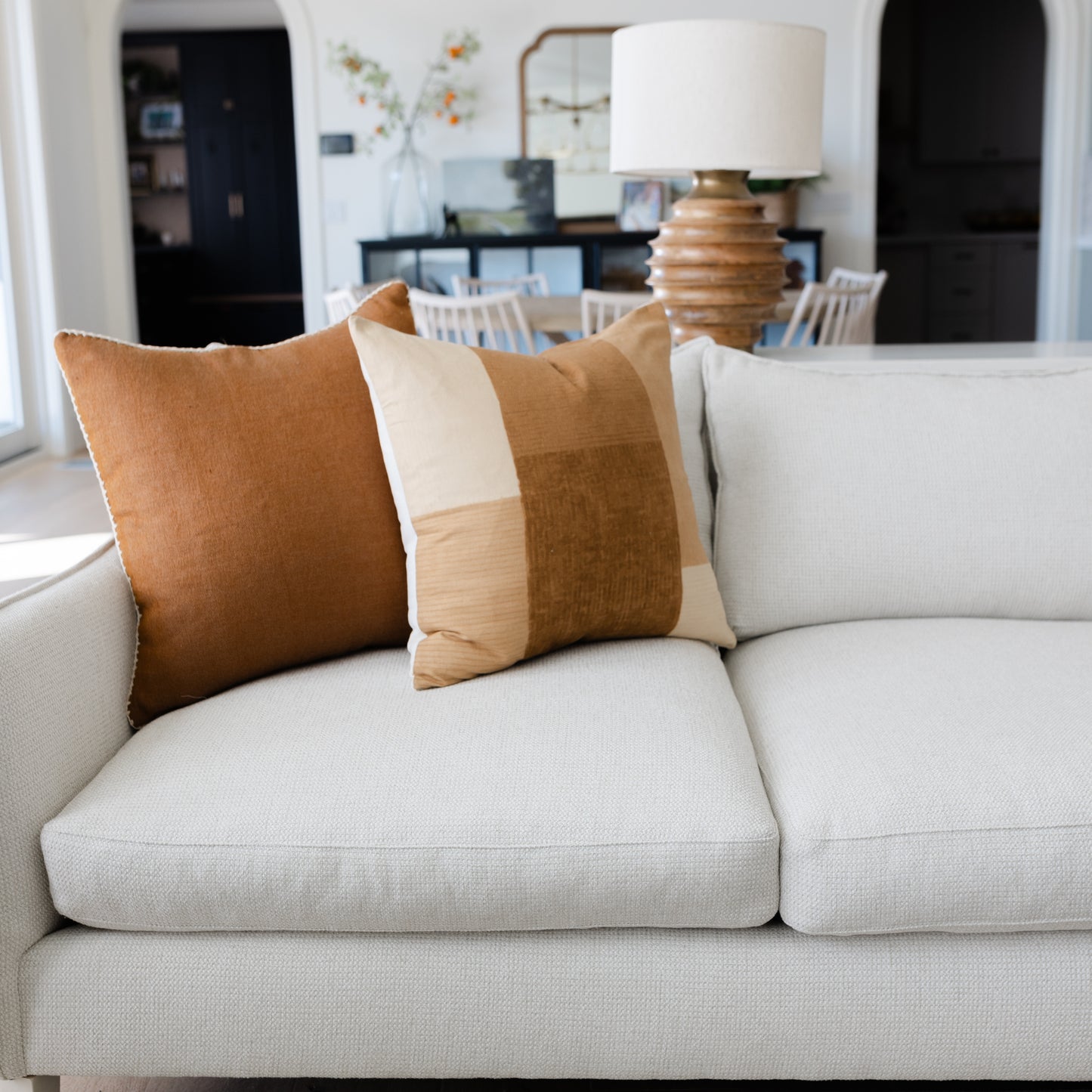 Tierra throw pillow in tan and cream colorblock stripe displayed on light gray sofa.