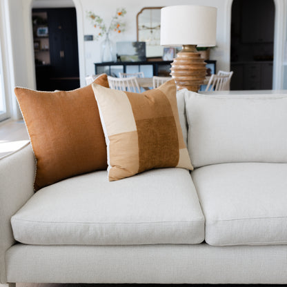 Tierra throw pillow in tan and cream colorblock stripe displayed on light gray sofa.