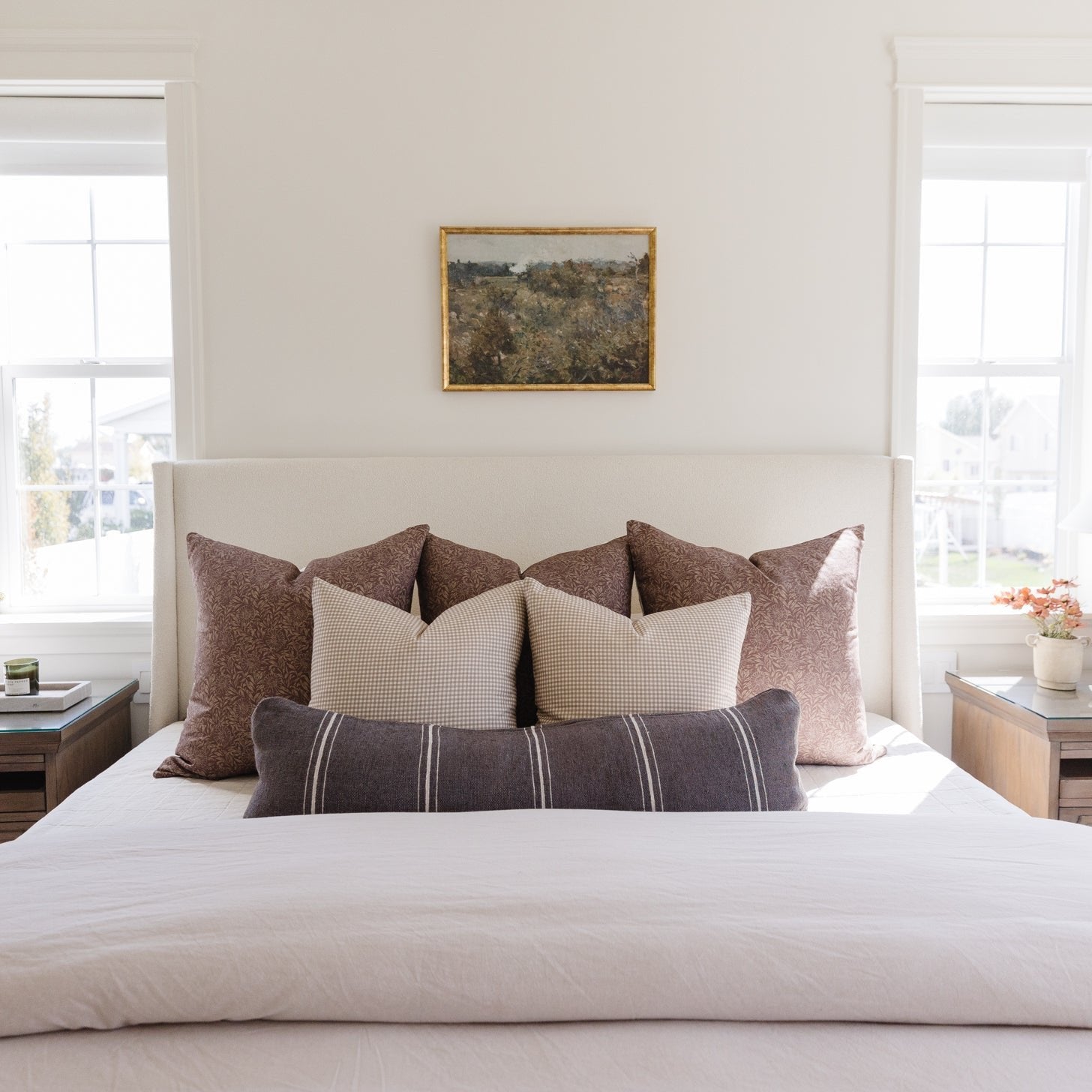 Warm charcoal lumbar pillow with striped pattern displayed on bed with coordinating pillows and bedding.