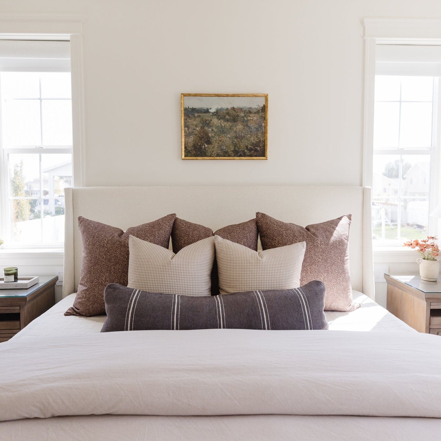 Warm charcoal lumbar pillow with textured weave displayed among coordinating pillows on a bed headboard.