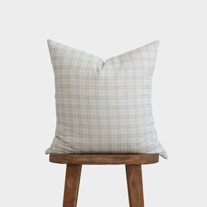 Cream and blue plaid pillow cover displayed on wooden stool.