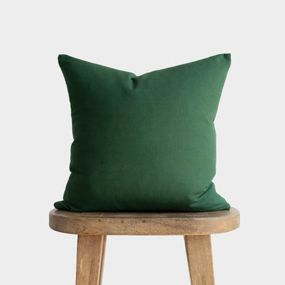Green pillow with envelope closure displayed on wooden stool.