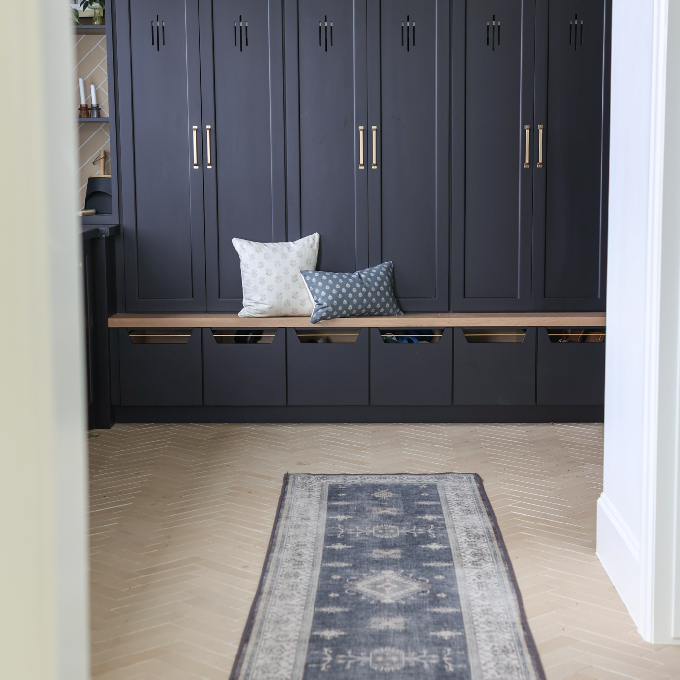 Blue lumbar pillow with geometric pattern displayed on entryway bench next to white pillow.