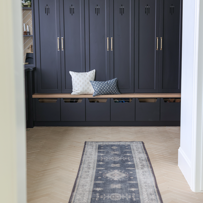 Blue lumbar pillow with geometric pattern displayed on entryway bench next to white pillow.