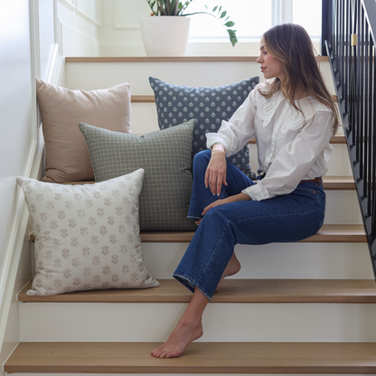 Blue Clay vintage pillow with white polka dot pattern displayed on wooden staircase with woman seated nearby.