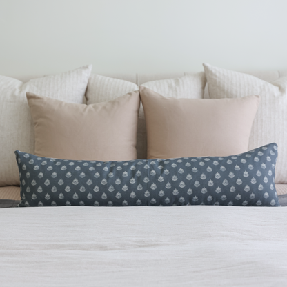 Tan solid pillow cover displayed on bed with white striped and patterned blue pillows.