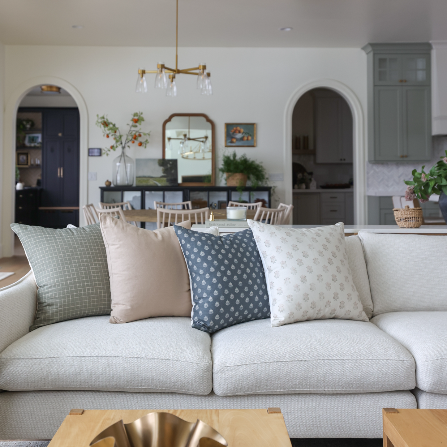 Blue patterned throw pillow displayed on a cream upholstered sofa in a living room setting.