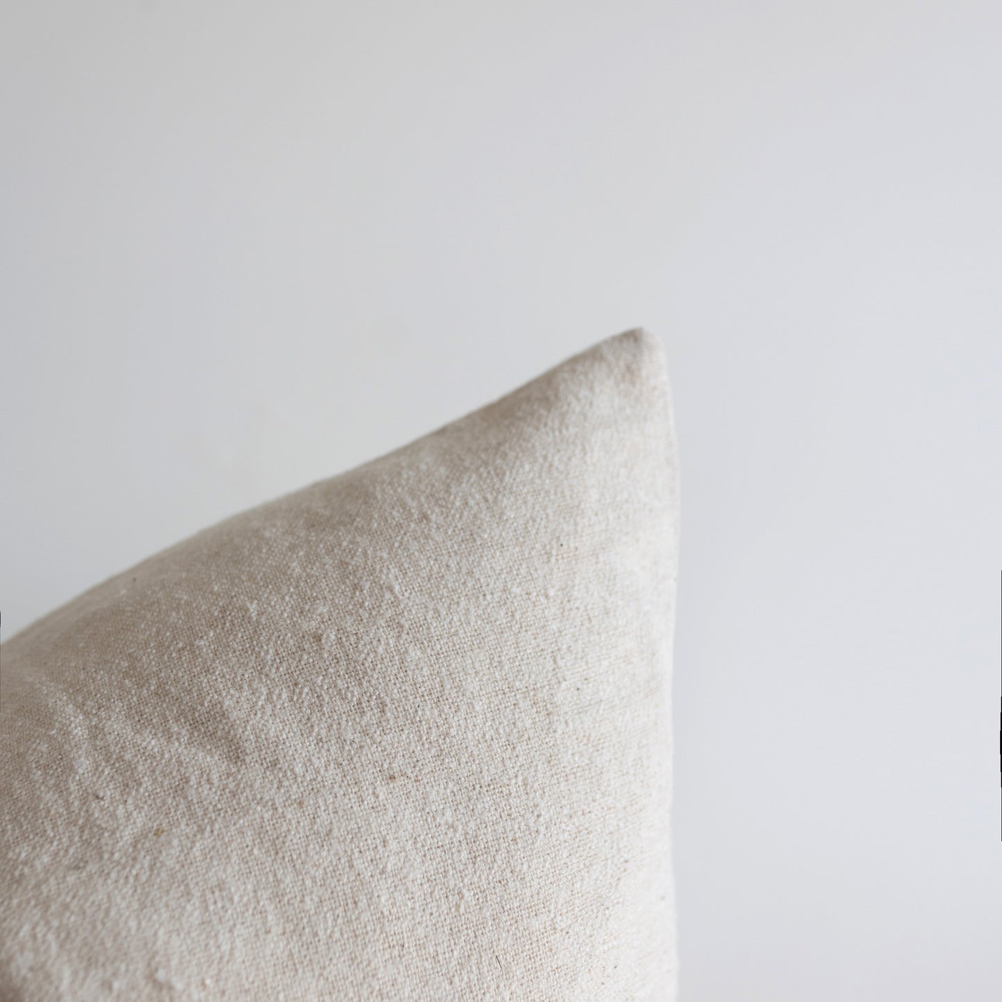 Off-white boucle pillow with textured fabric weave against neutral background.