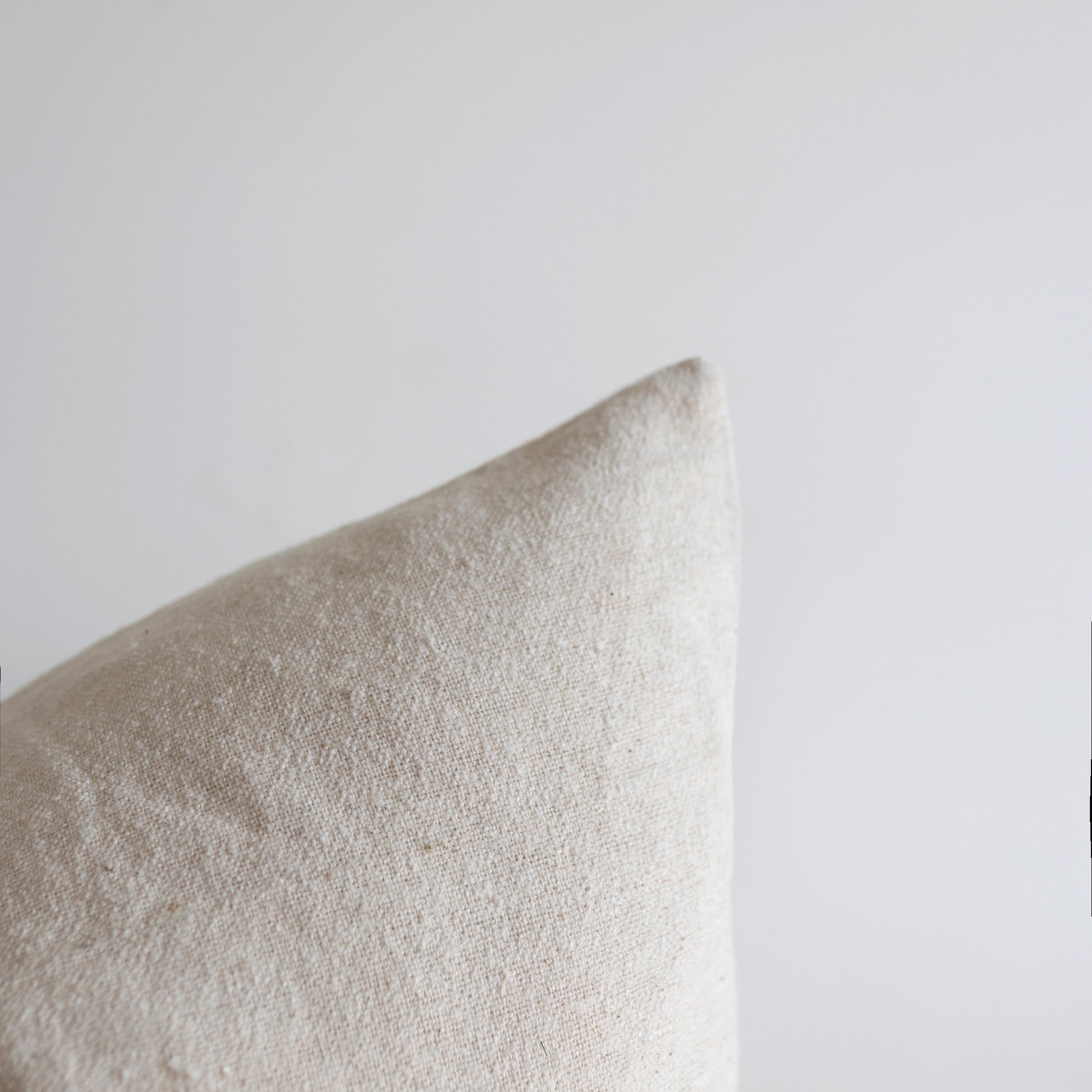 Off-white boucle pillow with textured fabric weave against neutral background.