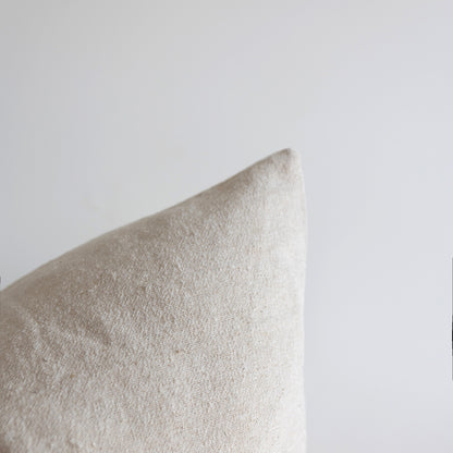 Off-white boucle pillow with textured fabric weave against neutral background.