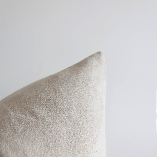 Off-white boucle pillow with textured fabric weave against neutral background.