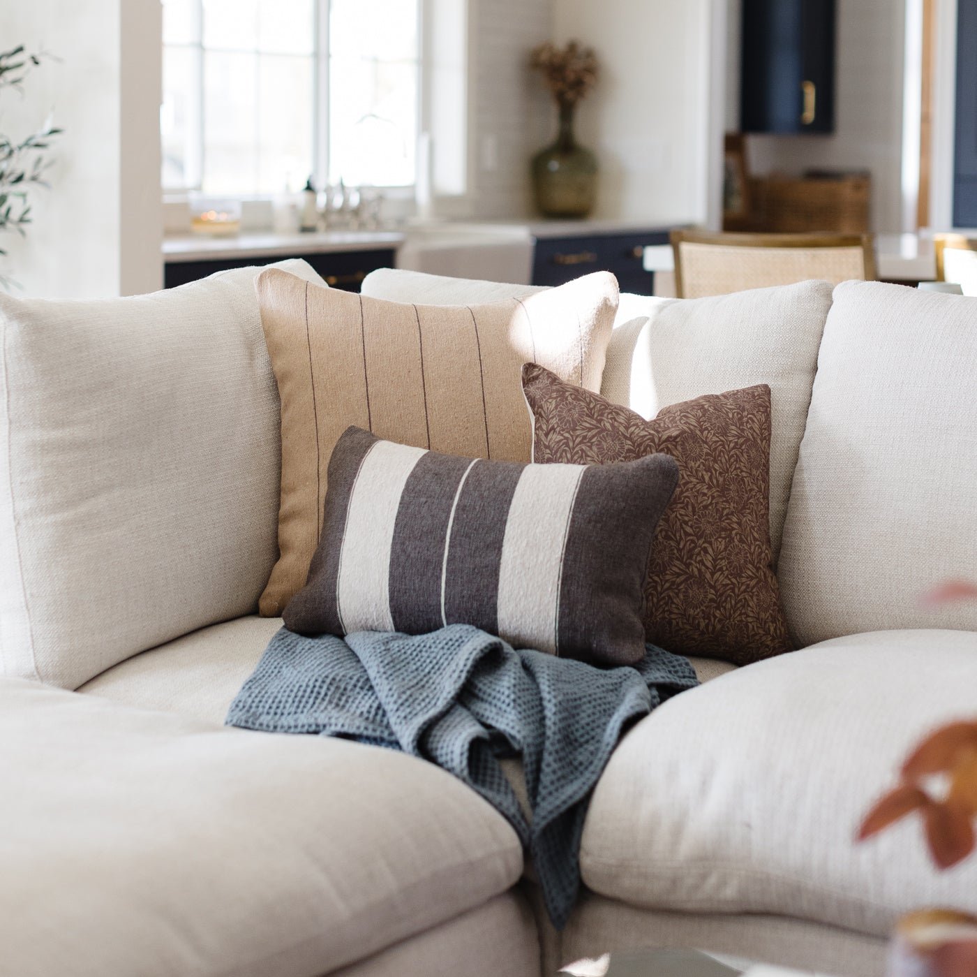 Storm blue waffle blanket draped over a cream-colored sofa with decorative pillows.