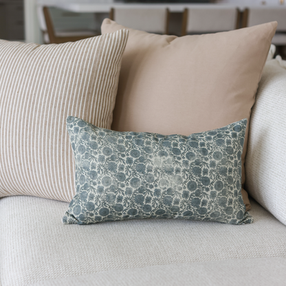 Blue and cream floral lumbar pillow with botanical leaf pattern on light sofa.