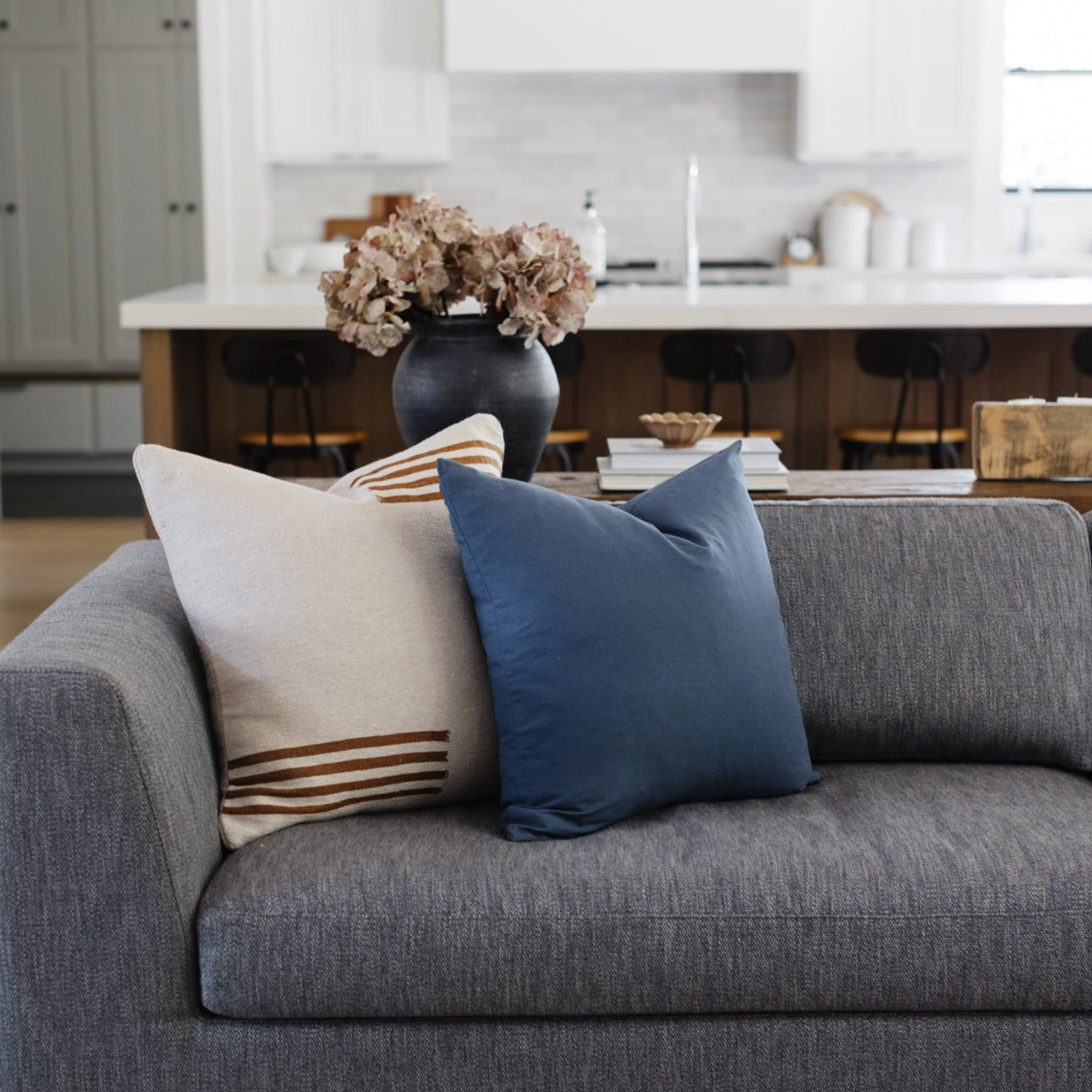 Navy blue and cream pillows arranged on a gray sofa in a modern living room setting.