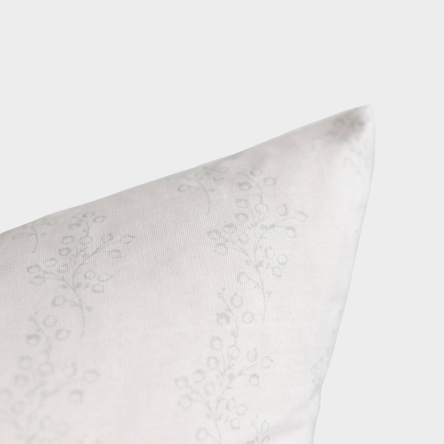 White pillow with subtle floral damask pattern, shown at an angle against neutral background.