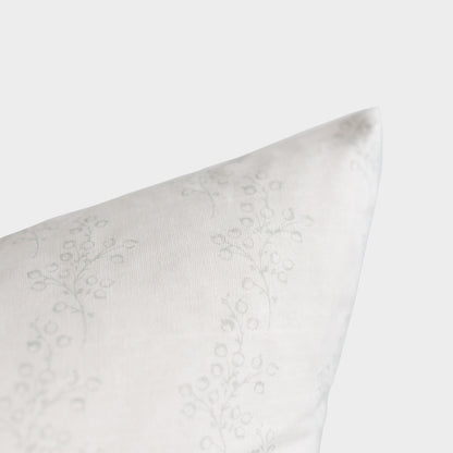 White pillow with subtle floral damask pattern, shown at an angle against neutral background.