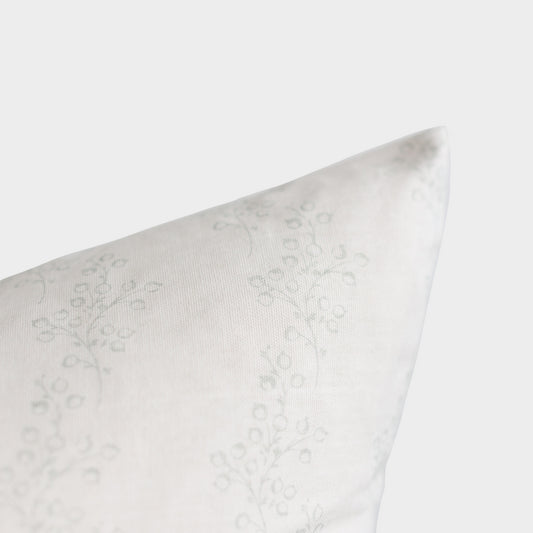 White pillow with subtle floral damask pattern, shown at an angle against neutral background.