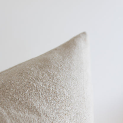 Off-white boucle pillow with textured woven surface shown at an angle.