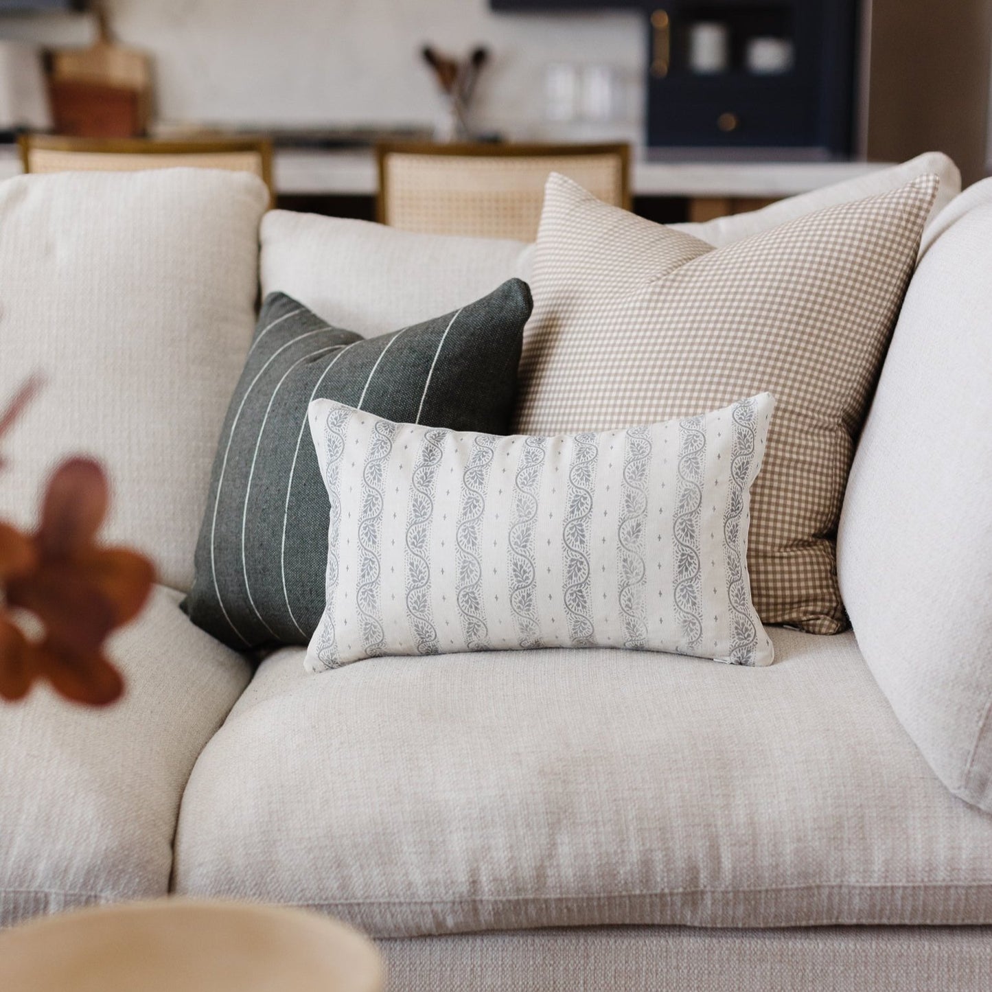 White lumbar pillow with gray paisley stripe pattern displayed on a beige sofa with coordinating accent pillows.
