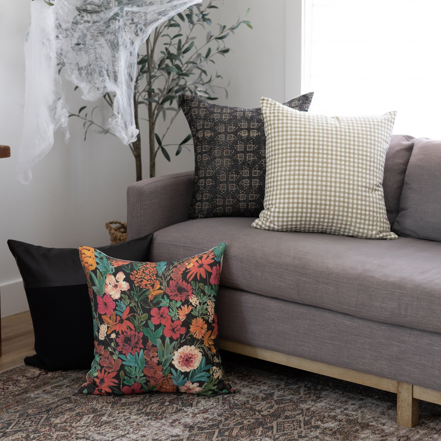 Throw pillow with dark background and multicolored floral pattern including red, orange, pink, and cream flowers with green f