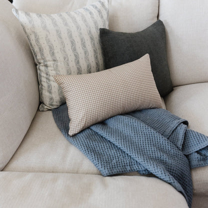 Storm blue waffle-textured blanket draped on a beige sofa with coordinating pillows.