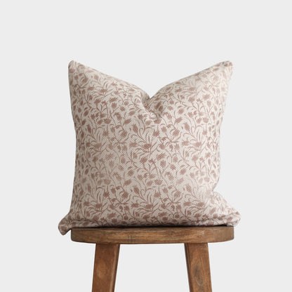Beige and taupe floral patterned pillow with thick weave fabric on wooden stool.